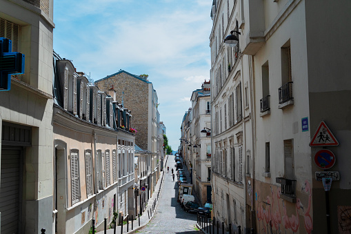 View of steep street in quarter Montmartre in Paris, France. Cozy cityscape of Paris at summer. Architecture and landmarks of Paris.