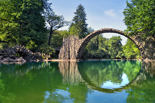 Devil's bridge from natural stone in the nature Park Kromlau with circle reflection in the water