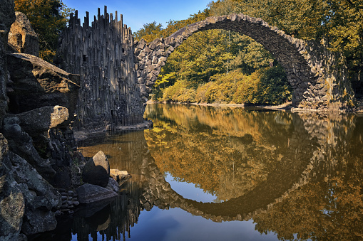 Devil's bridge in the nature park with circle reflection in the water
