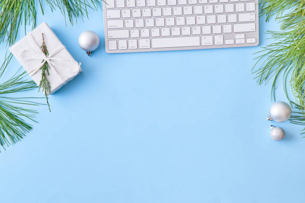 istock Flat lay christmas home office desk with pine branches and keyboard, christmas decorations on a blue background 1178196110