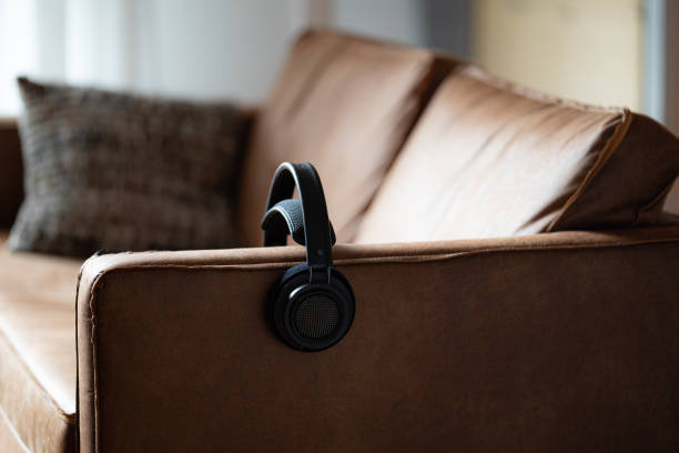 Music in the livingroom Wireless headphones on a sofa couch in the livingroom of a home for relaxing and listening to music berkel stock pictures, royalty-free photos & images