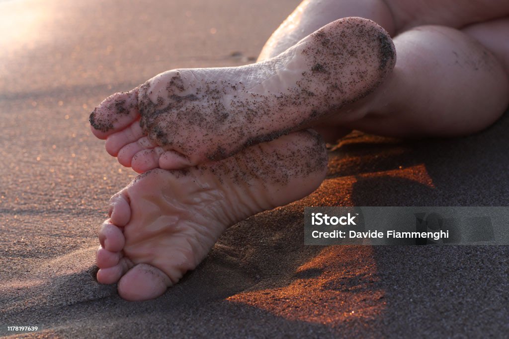 Piedi femminili sulla sabbia al tramonto - Foto stock royalty-free di Adulto