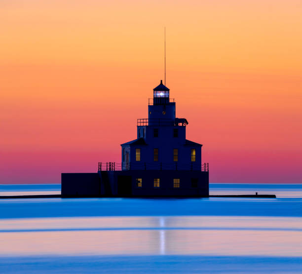 Lighthouse silhouetted in the warm light of summer twilight.
