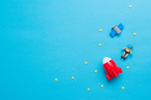 Spaceship, rocket and astronaut toys on blue background with blank space for text. Top view, flat lay.