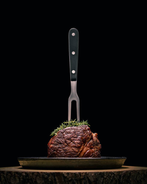 Sous-vide grilled beef steak with fork and herbs on dark background. stock photo