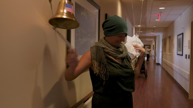 Young woman ringing a bell for finishing her last chemotherapy treatment