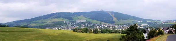 The Fichtelberg with the little town Oberwiesenthal in the Saxon part of the Erzgebirge in Germany, photographed from the Bohemian part in the Czech Republic, thunderclouds at one day a late summer, panoramic