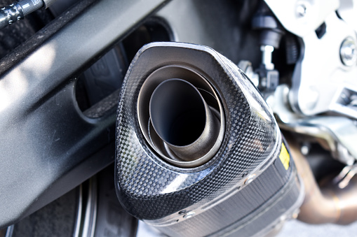 Close up view of a black carbon motorcycle exhaust pipe. Sport motorcycle, performance parts