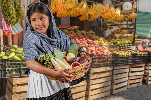 Little Latin girl with her basket full of local vegetables and fruit