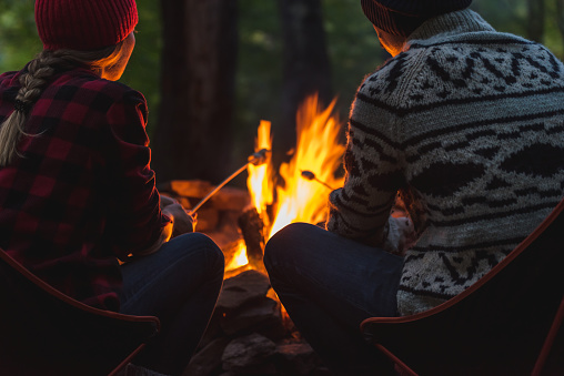 A young couple roasting marshmallows to make smores while camping.