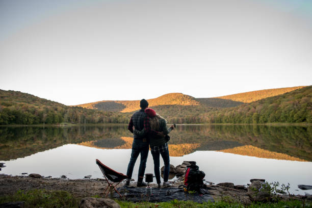 Couple relaxing near a lake while camping stock photo