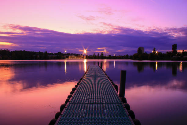 romantic sunset with purple sky and clouds reflected in symmetry on a lake. - water lake reflection tranquil scene imagens e fotografias de stock