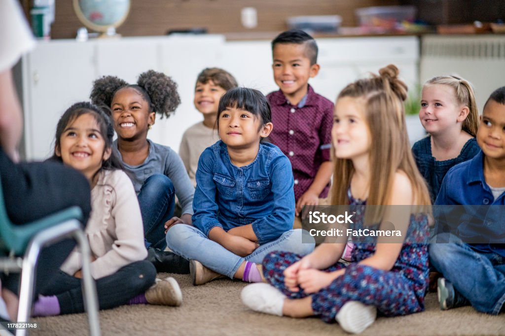 Diverse kids in a classroom Multi-ethnic group of school children. Storytelling Stock Photo