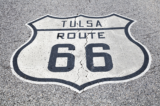 A black and white road sign of the historic Route 66 on asphalt.