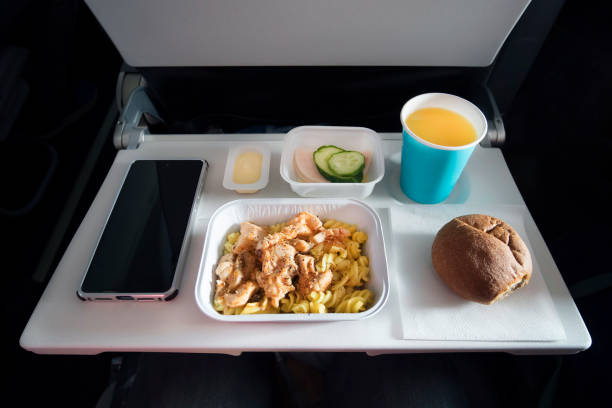 istock Various economy class food and a passenger smartphone with a blank screen on the folding table of the aircraft. Meals on Board the aircraft. plastic Cutlery knife and fork in a plate with food. 1178229712