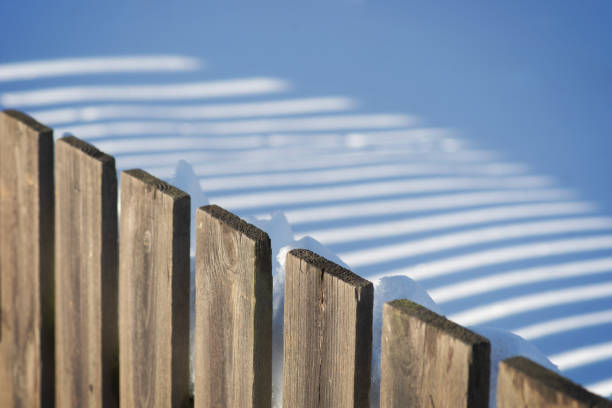 istock Wooden fence casting shadow on snow 1178235709