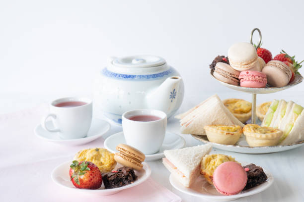 High Tea Horizontal High Tea with Macaroons, Sandwiches, Quiche, Brownies and Strawberries with Tea Horizontal afternoon tea stock pictures, royalty-free photos & images