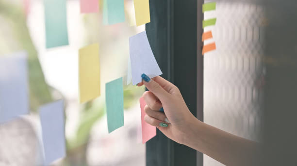 istock Businesswoman reading sticky notes on glass wall with her working. 1178248964