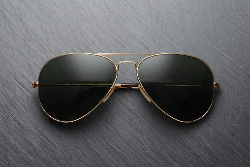 Classic old fashion metal sunglasses on black slate background. Top view