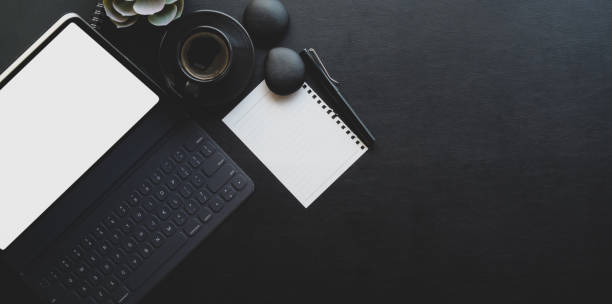 Dark trendy workplace with tablet and office supplies on black leather background
