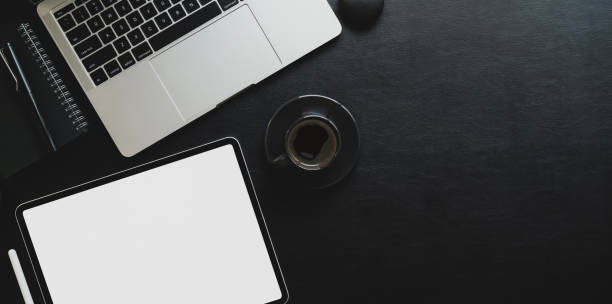 istock Top view of dark workplace with blank screen tablet and laptop computer 1178252868