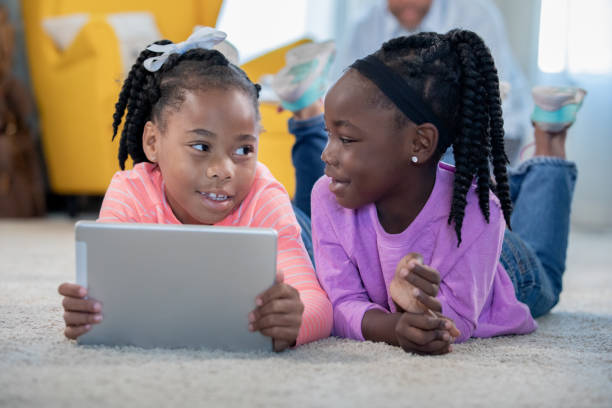 istock Sisters laying in floor playing on digital tablet 1178253949