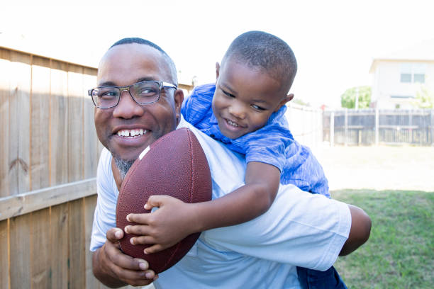 father and young boy playing football outside - playing catch imagens e fotografias de stock