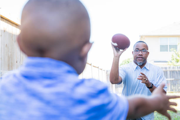 istock Dad throwing football to young son 1178254808