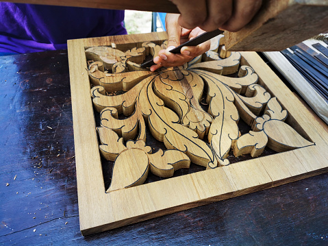 Skilful carpenter carving plant and leaves motif wood carving.