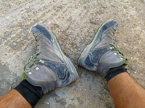close up of exhausted male feet with dusty boots after hike.
