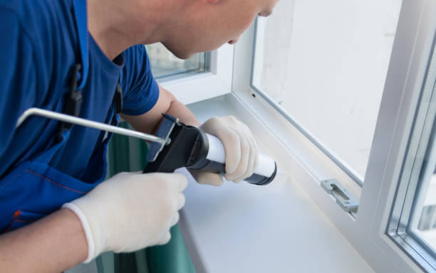 istock master in protective gloves, seals the cracks of the plastic window with white silicone, close-up 1178262132