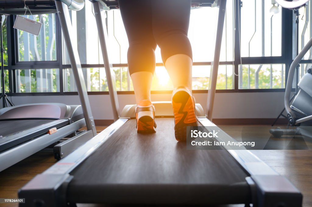 Workout 1 leg of fat woman being run or jog on belt of treadmill machine Overweight Stock Photo
