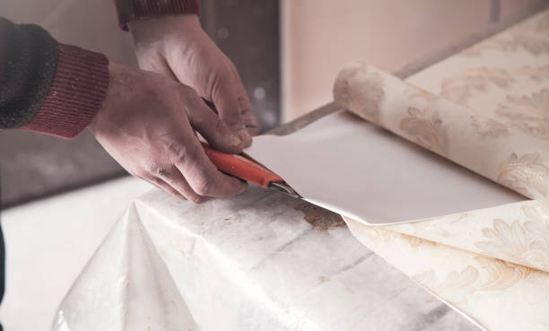 istock Worker cutting wallpaper. Apartment repair 1178264348