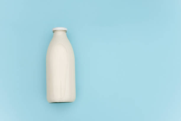 Milk in glass bottle on blue background with copy space. Flat lay Top view stock photo