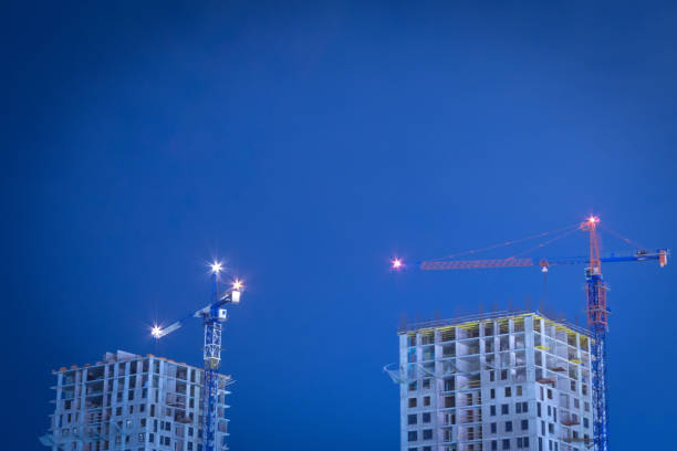 istock two construction cranes at night building houses 1178271538