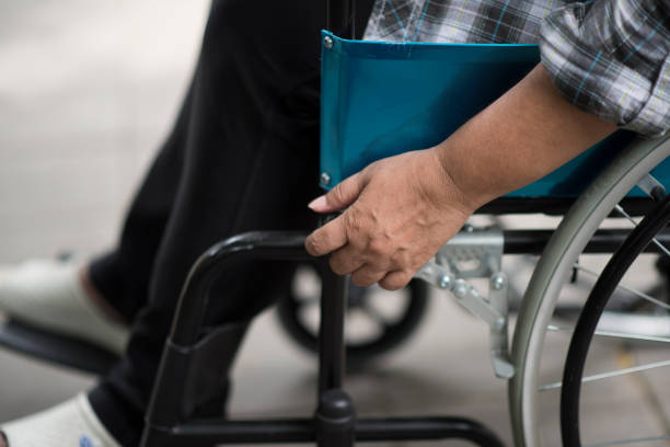 nahaufnahme der seniorin hand auf rollstuhlrad während eines spaziergangs im krankenhaus - sclerosis stock-fotos und bilder