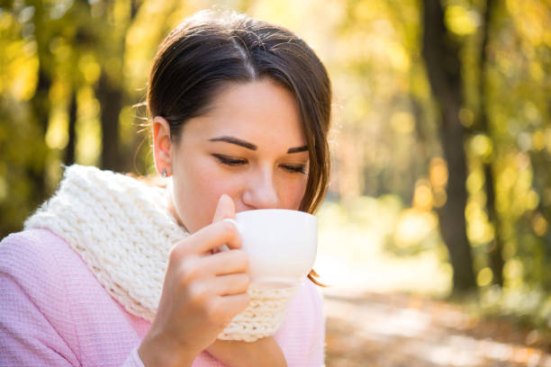 istock girl drinks from a cup in autumn park 1178285514
