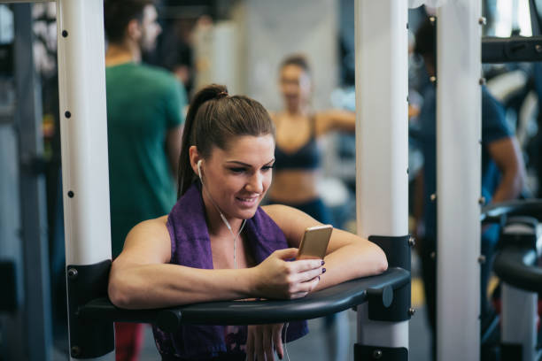 istock Woman using phone while resting from exercising at gym 1178285624