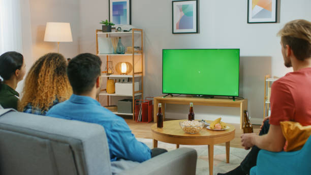 istock Happy Friends Sitting At Home Watching Green Chroma Key Screen, Relaxing on a Couch. Watching Sports Match, News, Sitcom TV Show or a Movie. 1178291849