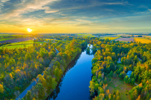 Amazing Autumn trees line tranquil river at sunrise.
