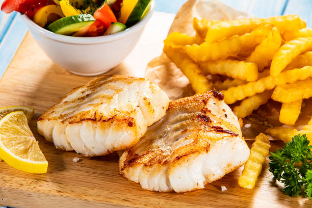 Fried cod fillet with French fries and vegetables Fried cod fillet with French fries and vegetables curly fries stock pictures, royalty-free photos & images