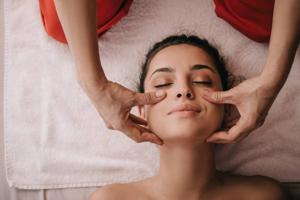 cropped view of masseur doing face massage to woman in spa salon cropped view of masseur doing face massage to woman in spa salon facial massage stock pictures, royalty-free photos & images