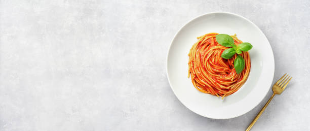 istock Top view of plate eith pasta in tomato sauce and basil on white background 1178303494