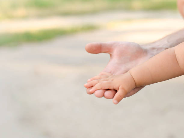 istock little baby hand with father's hand on light background with copy space 1178303614