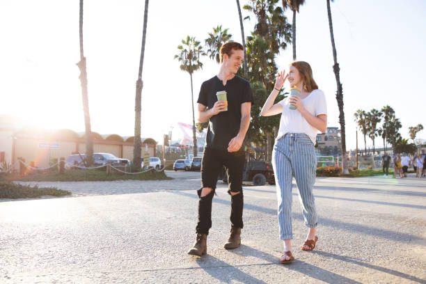 jeunes couples romantiques appréciant le café sur des tasses réutilisables - santa monica beach city of los angeles california photos et images de collection