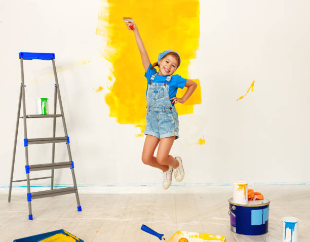 riparazione in appartamento. felice bambina che salta dipinge muro - 11915 foto e immagini stock