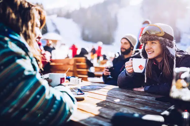 Photo of Happy skiers talking on a break in a cafe at mountain.