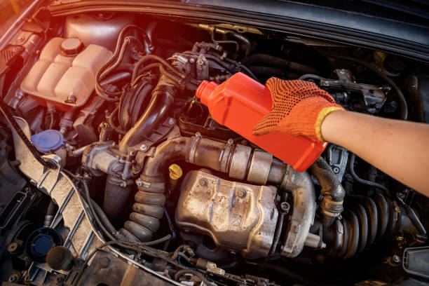 istock Male hands with oil bottle above car engine 1178311435