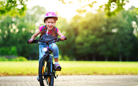 happy cheerful child girl riding a bike in Park in the nature