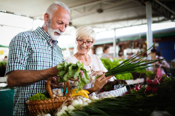 pareja madura comprando verduras y frutas en el mercado. dieta saludable. - supermarket shopping retail choice fotografías e imágenes de stock